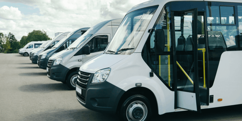 Row of white commercial minibuses parked in a line, ready for business transport use.